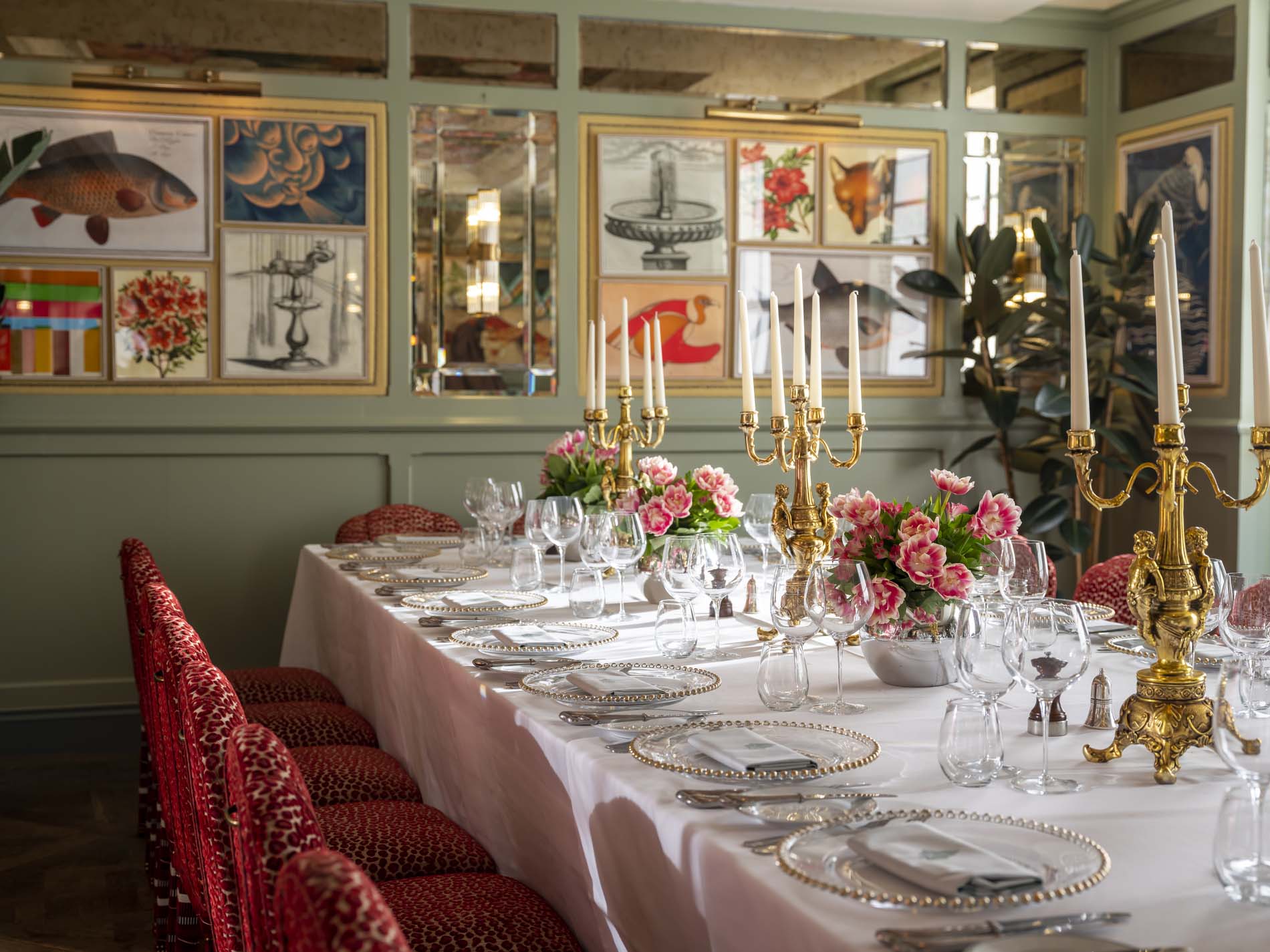 A close up image of the inside of the Isabella room. There is a long table in the centre with white table cloth and candles. there are 3 flower posts with pink roses on the table.